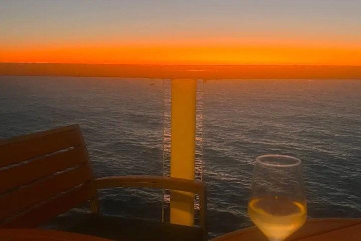 Sunset view from a balcony with a wine glass on a table.