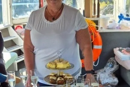Woman in sunglasses with cakes and desserts on a table.
