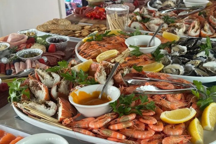 Seafood platter with shrimp, oysters, crab, and lemon wedges.