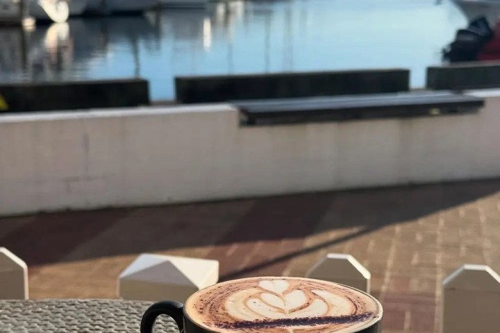 Cup of cappuccino on table with marina view.