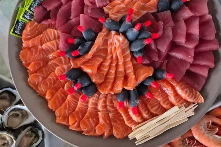 Plate of assorted sashimi with salmon, tuna, lemon slices, and garnish.