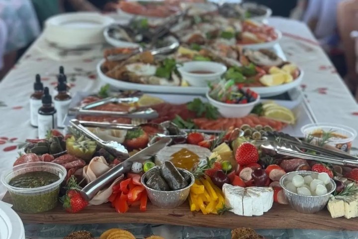 Table with assorted appetizers, crackers, dips, and people in background.